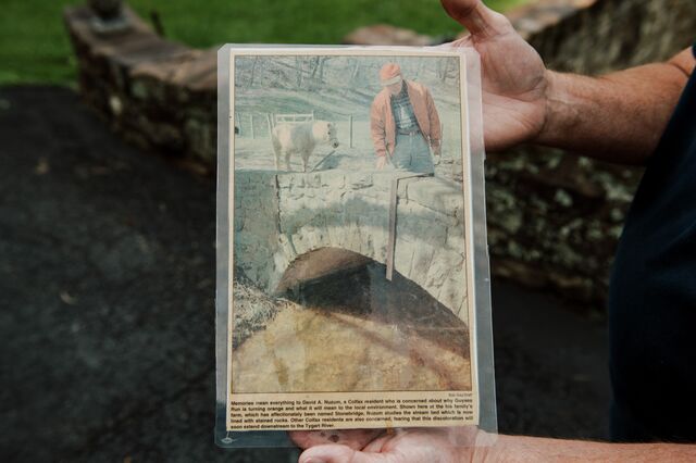 Nuzum holds a newspaper clipping from the 1990s, when the creek flowing behind his house turned orange.