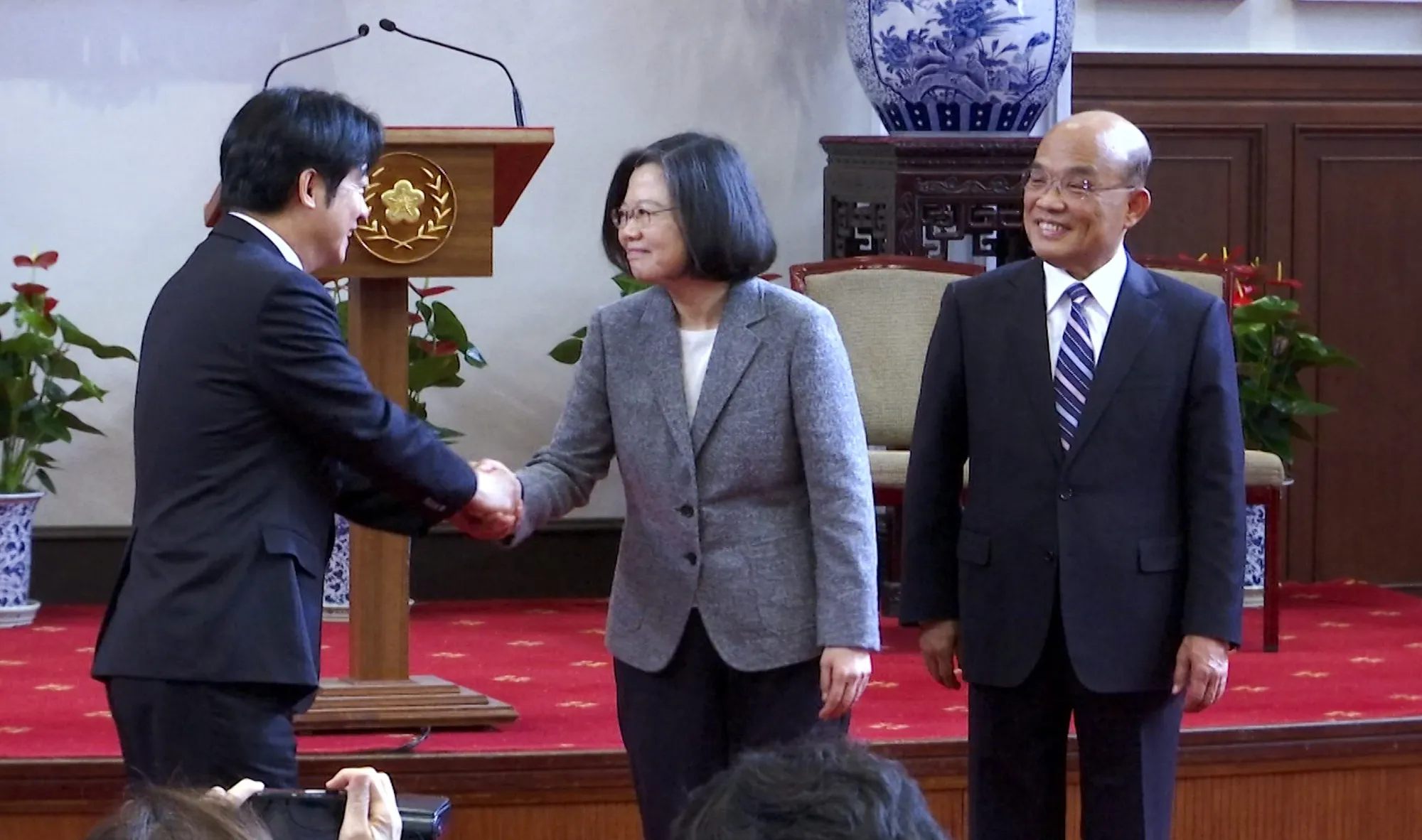 Lai Ching-te, left, shakes hands with Tsai Ing-wen, center.