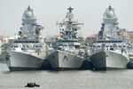 Indian naval sailors on a rubber inflatable boat pass naval warships at the Naval Dockyard in Mumbai.
