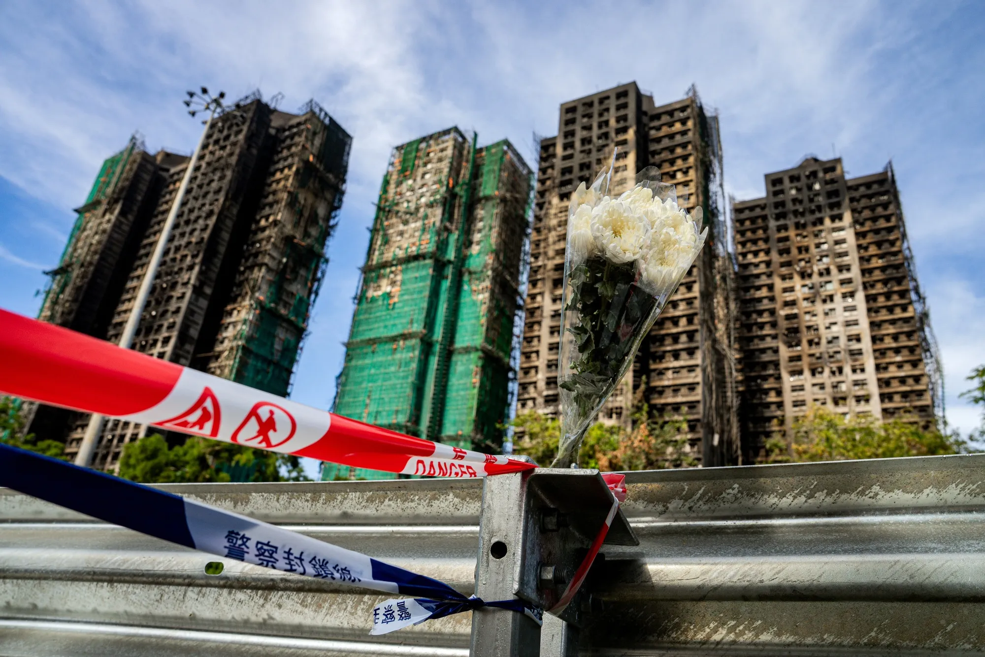 Floral tributes for victims of the fire at Wang Fuk Court residential estate left on a barrier in Tai Po district in Hong Kong, China, on Friday, Nov. 28, 2025.