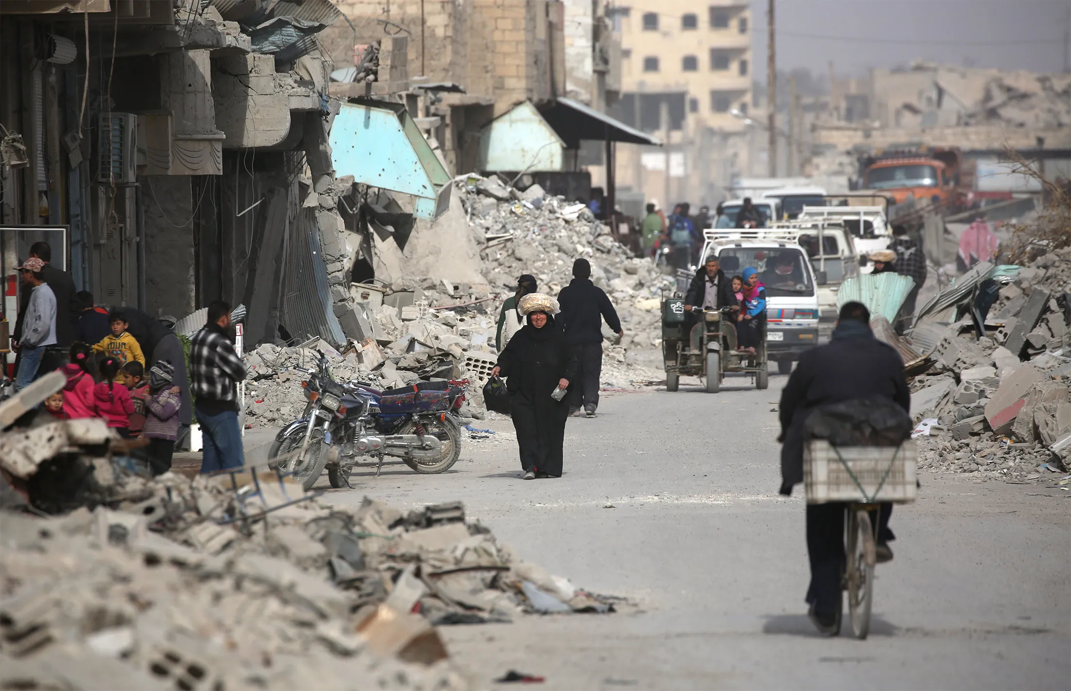 Syrians walk amidst the debris of destroyed buildings in the northern Syrian city of Raqa, on Jan. 11, 2018.
