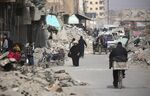 Syrians walk amidst the debris of destroyed buildings in the northern Syrian city of Raqa, on Jan. 11, 2018.
