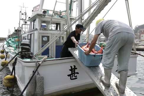 Fishermen unload a basket of fish at Inatori port in Japan