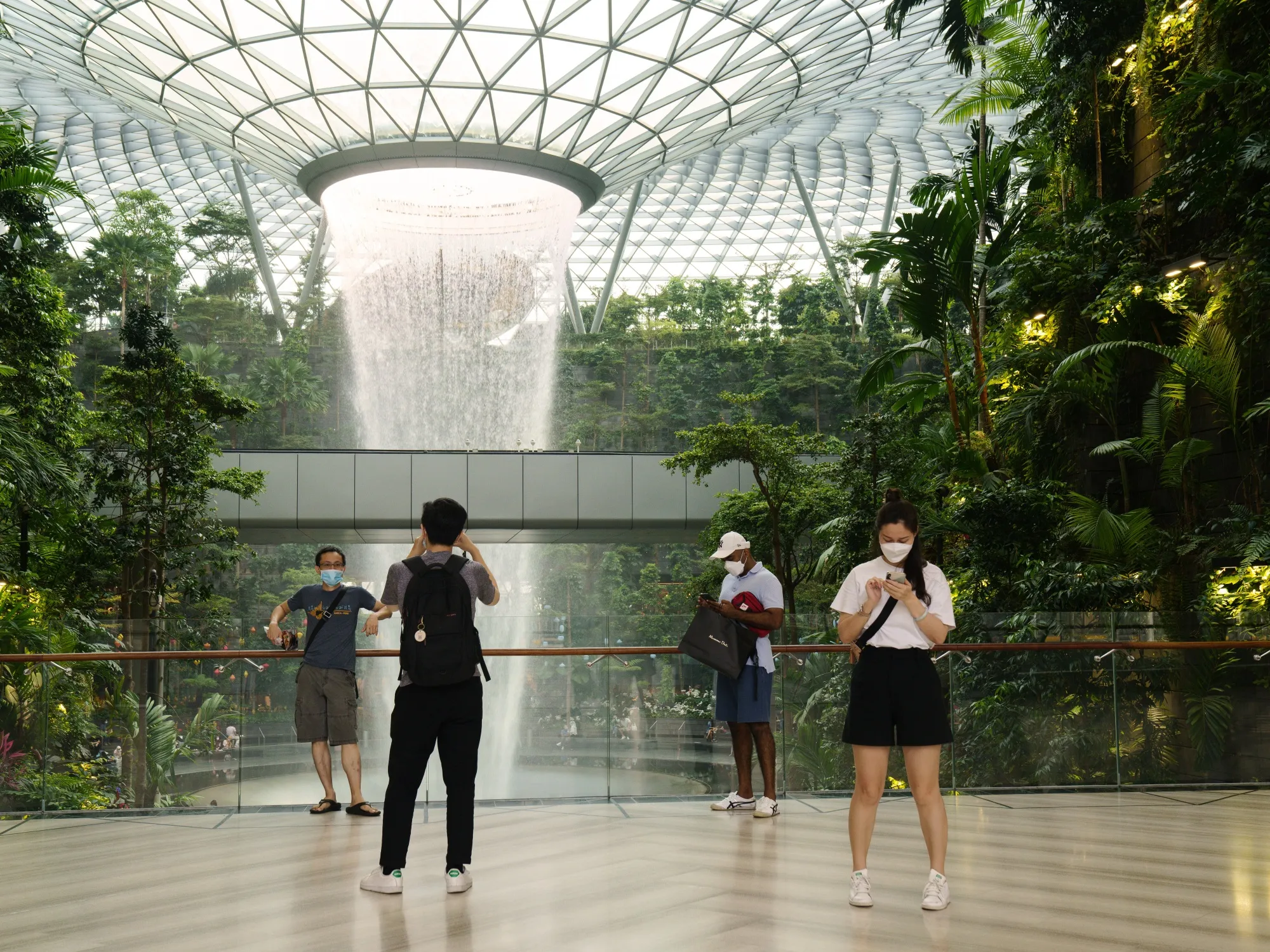 Visitors at the Rain Vortex, an indoor waterfall feature at the Jewel Changi Airport mall in Singapore, on Oct. 3. Singapore Trade Minister&nbsp;Gan Kim Yong said the government is committed to reopening the country gradually after reimposing domestic curbs to deal with a surge in coronavirus cases.