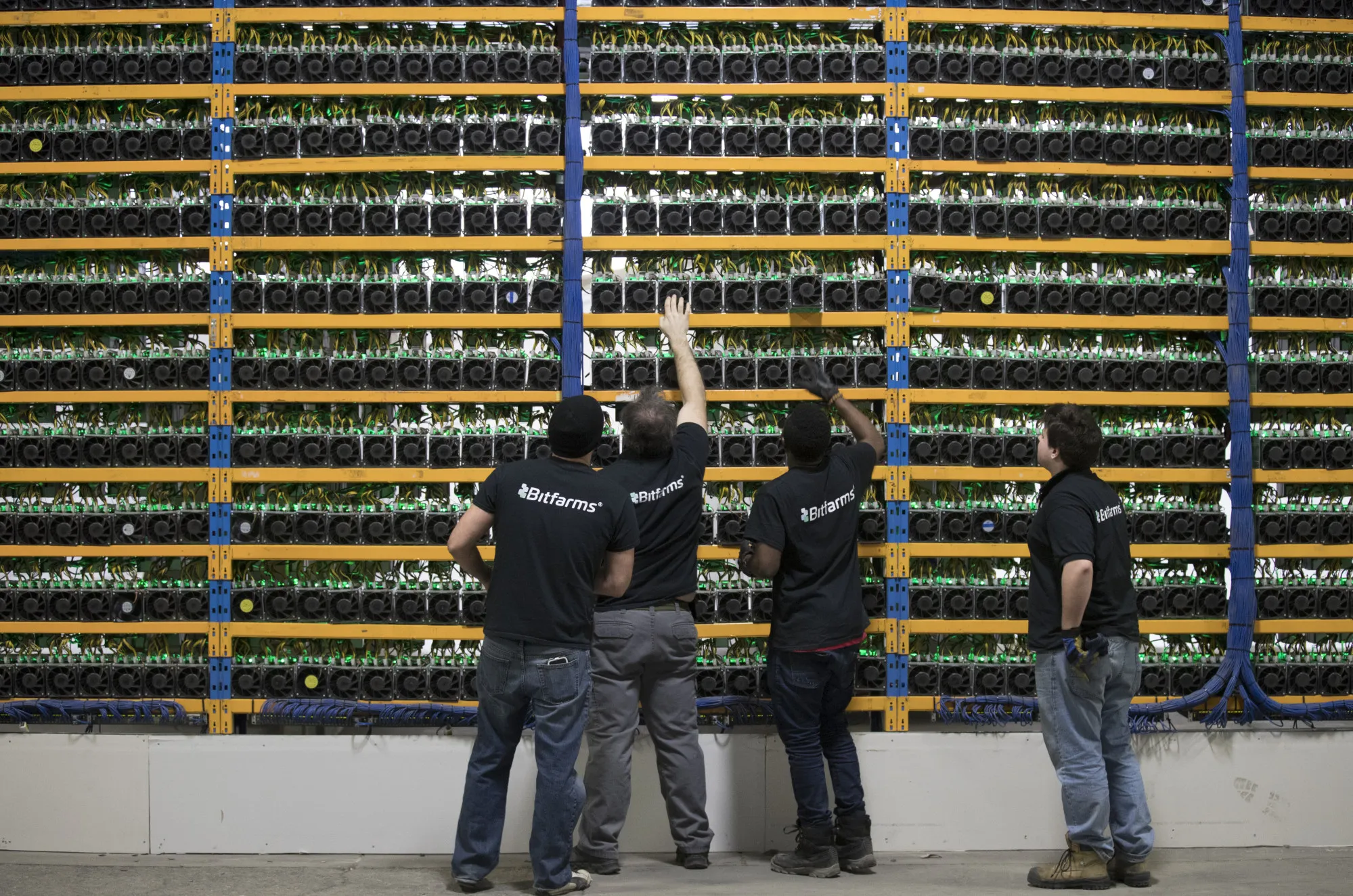 Employees check fans on mining machines at the Bitfarms cryptocurrency farming facility in Farnham, Quebec.