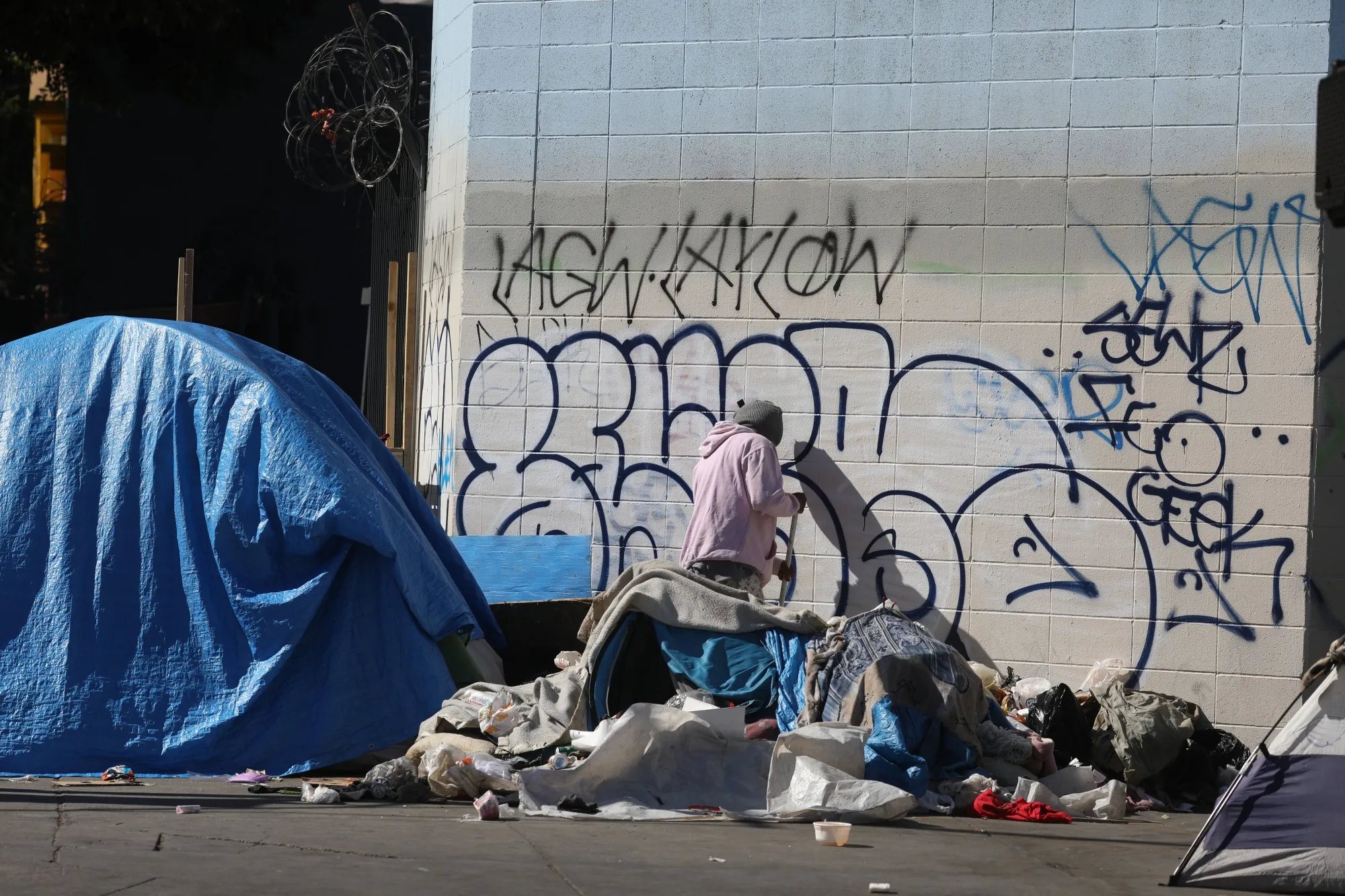 A person experiencing homelessness near their tent in the Skid Row neighborhood of Los Angeles.