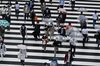 Pedestrians walk on a zebra crossing outside Shinjuku station in Tokyo