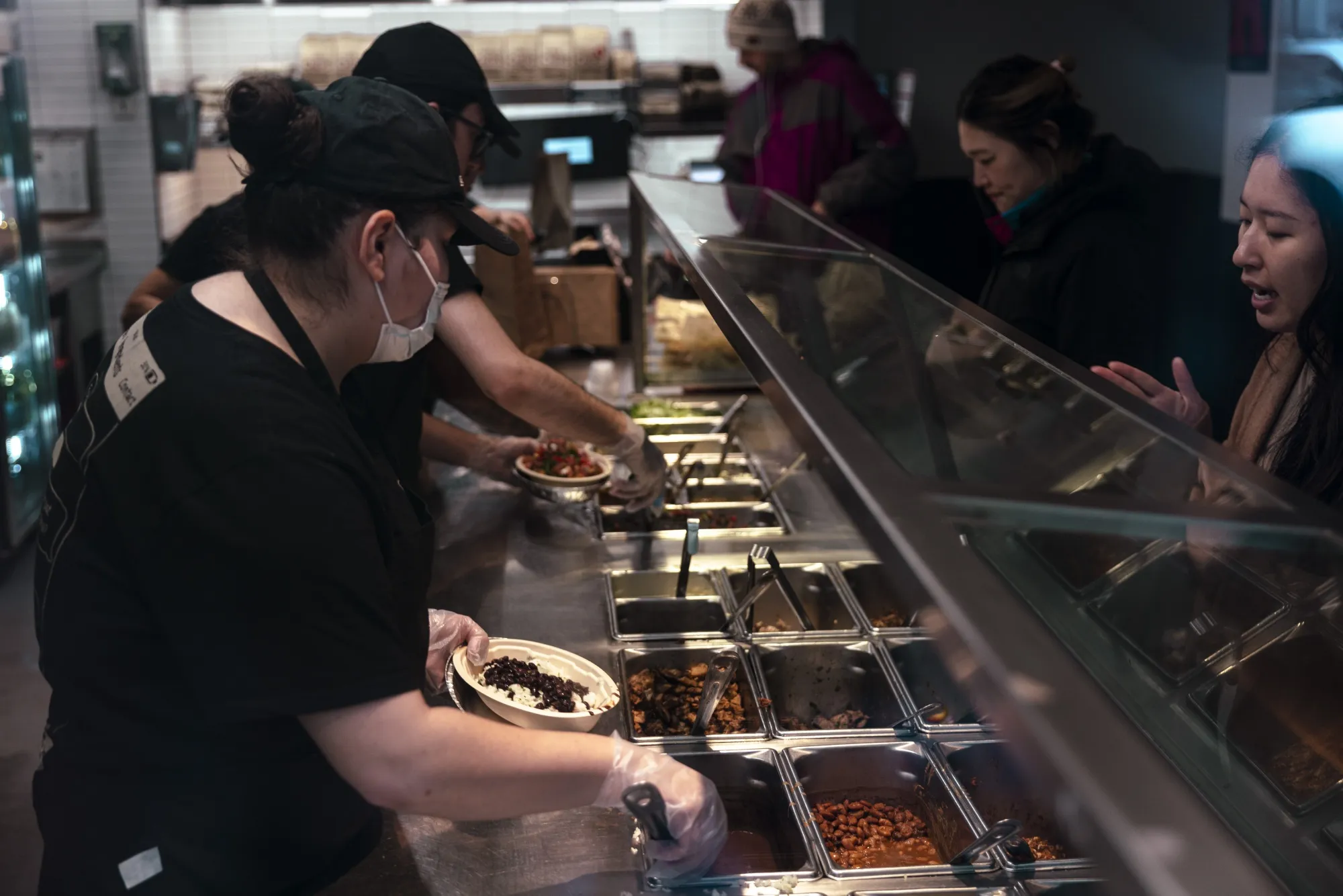 Workers serve food inside a Chipotle restaurant in New York.