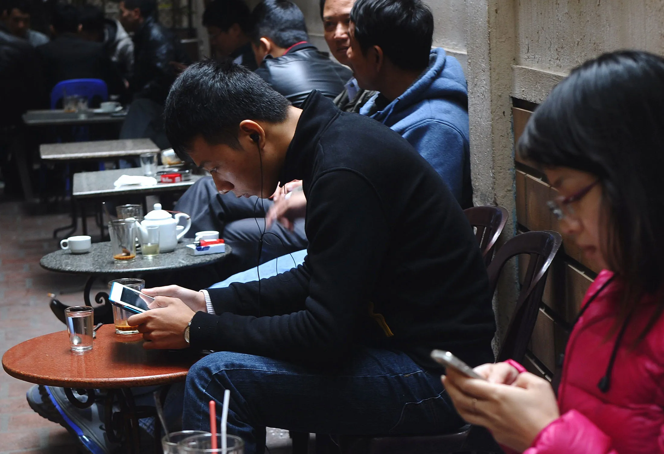 Customers use mobile devices at a coffee shop in Hanoi.&nbsp;