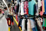 A worker hangs clothing on a conveyor system at the ThredUp sorting facility in Phoenix in 2019. 