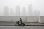 A man on an electric bike rides through heavy smog in Shanghai, China.