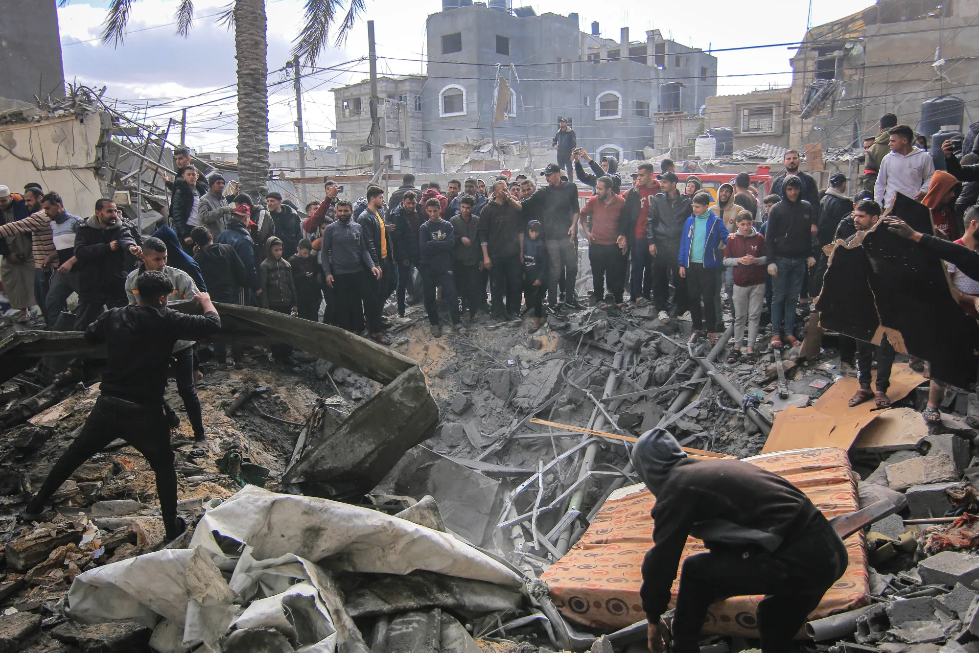 Palestinians search the rubble of buildings destroyed by an Israeli airstrike in Khan Younis, southern Gaza, on Friday, Jan. 12, 2024. 