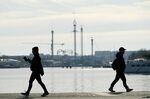 Pedestrians walk near the Skeppsholmen ferry terminal, in view of the Grona Lund amusement park, which has temporarily closed due to the coronavirus, in Stockholm, on&nbsp;March 26.