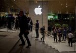 An Apple logo is illuminated as customers walk through the new Apple Inc.