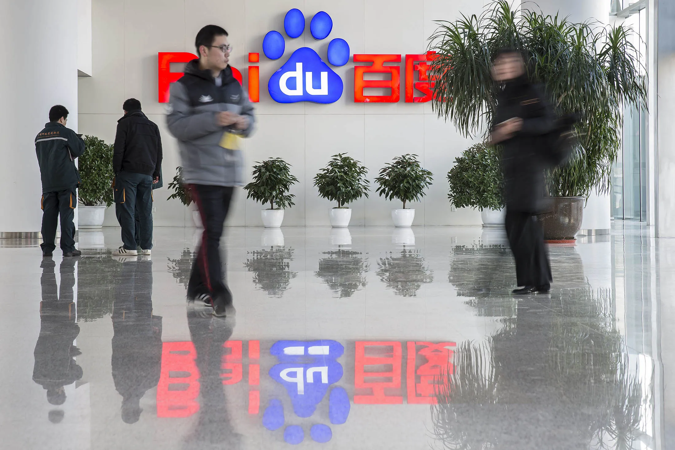 People walk past a Baidu Inc. logo displayed in the reception area of the company's headquarters in Beijing, China, on Jan. 19.
