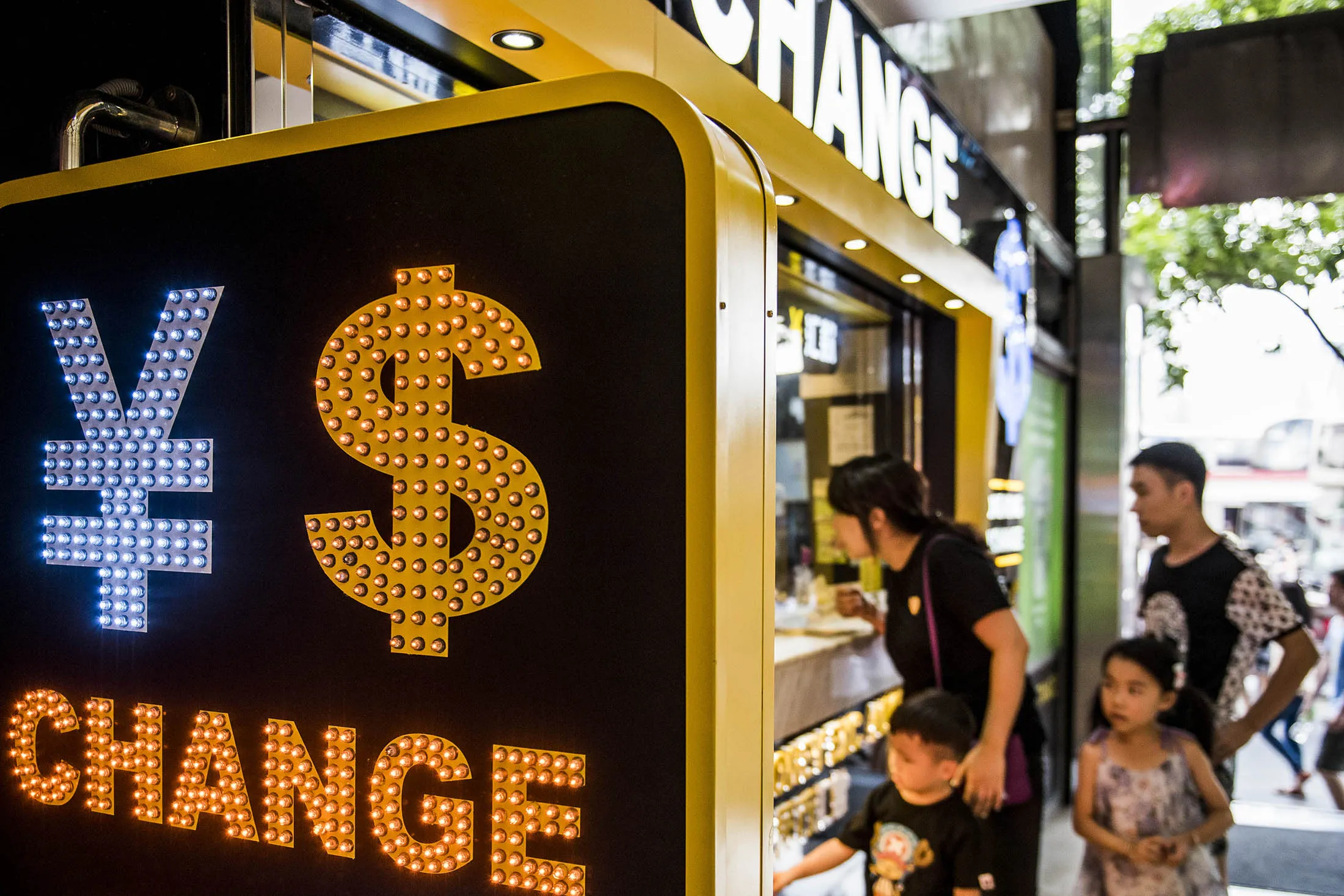 The currency symbol for the Chinese yuan and the dollar is displayed at a currency exchange store in Hong Kong, China, on Wednesday, Aug. 12, 2015. The yuan sank for a second day, spurring China's central bank to intervene as the biggest rout since 1994 tested the government's resolve to give market forces more sway in determining the exchange rate.
