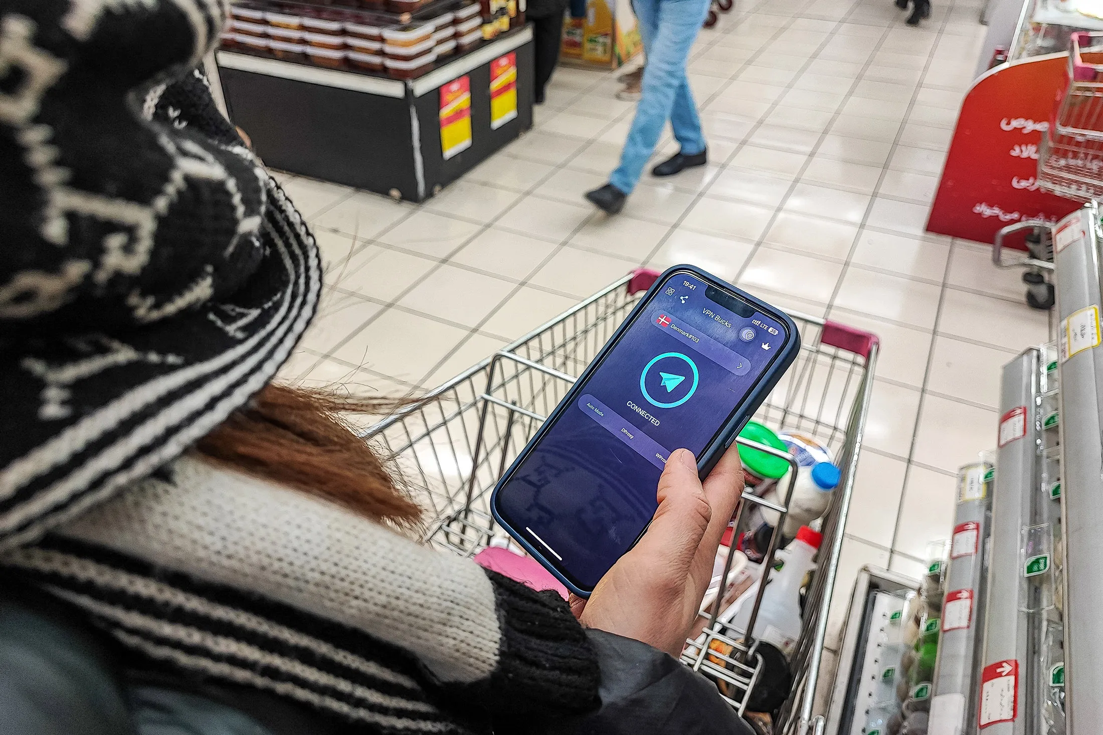 An Iranian holds a phone after activating a virtual private network (VPN) service to access the internet while shopping in a supermarket in Tehran, Iran.