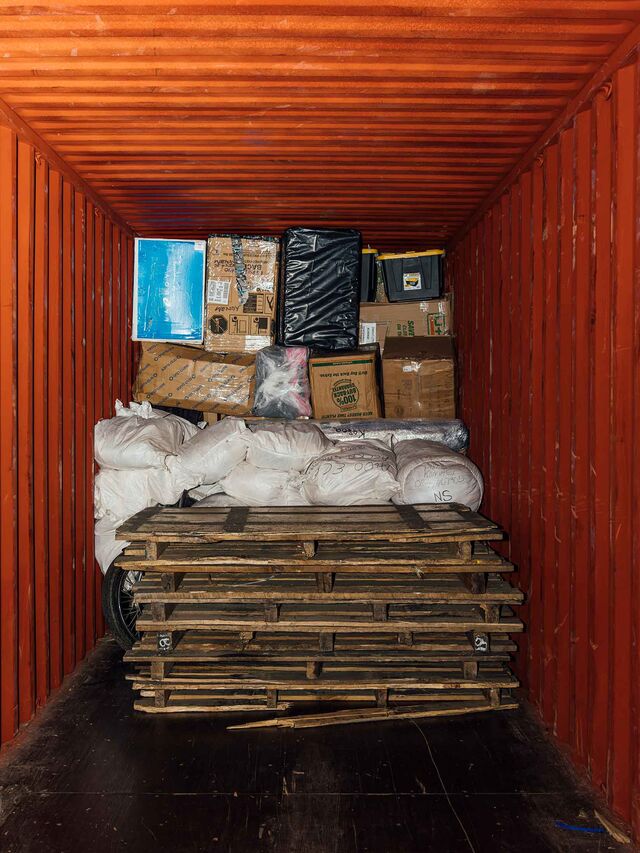 Interior photo showing a partially filled shipping container stacked floor to ceiling with goods, obscuring the vehicle behind the goods.