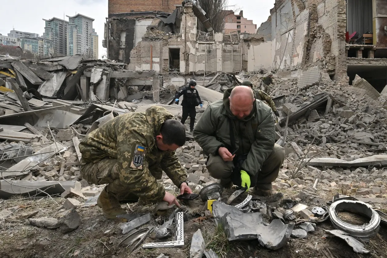 Ukrainian law enforcement officers examine fragments of a rocket at the site of a missile attack in Kyiv on March 25.