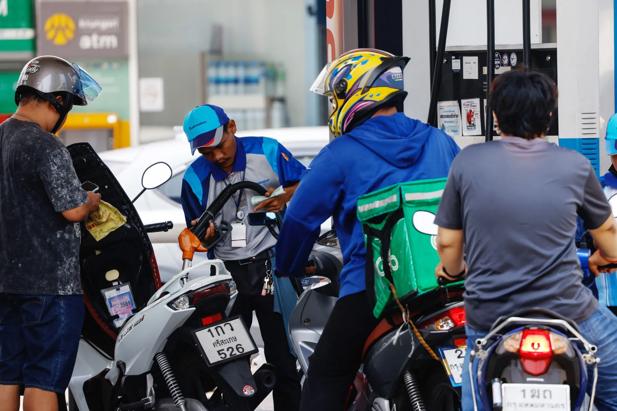 Motorcyclists refuel at a petrol station in Bangkok.