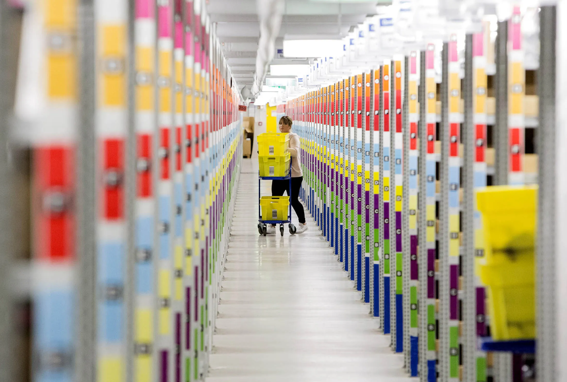 An employee pushes a cart between aisles of merchandise while collecting items for customers' delivery orders inside an Amazon.com Inc. fulfillment center in Koblenz, Germany, on Tuesday, Nov. 29, 2016. E-commerce sales in November and December will grow 17.2 percent to $94.7 billion, more than five times the pace of total retail sales growth of 3.3 percent, according to EMarketer.

