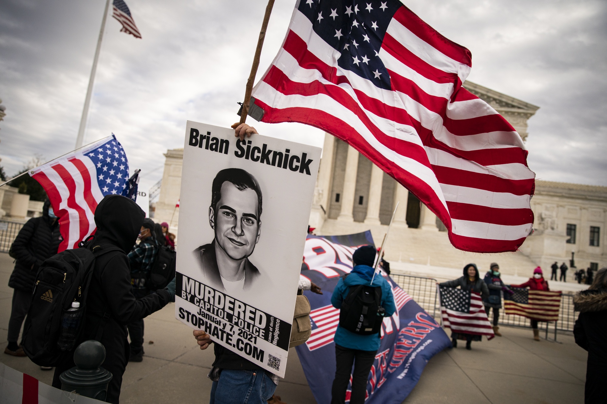 A demonstrator holds a sign on Friday with the likeness of Brian Sicknick, a Capitol Police officer who died after the Jan. 6, 2021 insurrection.&nbsp;