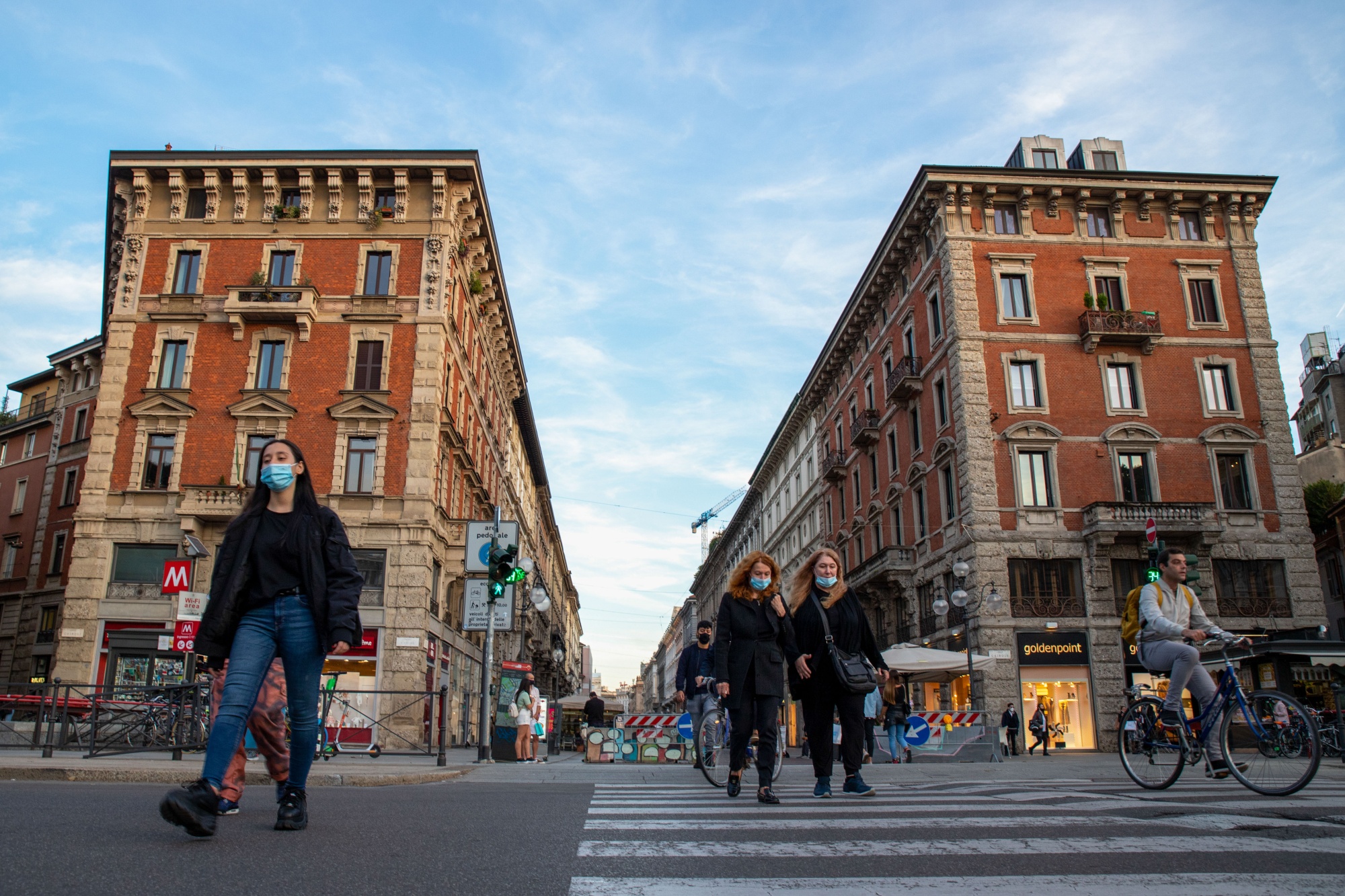 Pedestrians wearing protective face masks cross a street in Milan, Italy, on&nbsp;Oct. 8.
