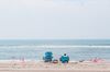 A couple sits on a beach while using a set of American flags to create a social distancing barrier around them in the Queens Borough of New York, on July 1.