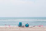 A couple sits on a beach while using a set of American flags to create a social distancing barrier around them in the Queens Borough of New York, on July 1.