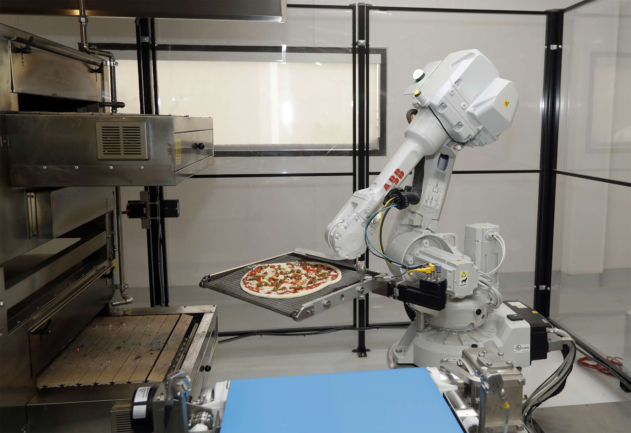 A robot places a pizza into an oven at Zume Inc. in Mountain View, Calif.