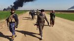 Members of the Kurdish Peshmerga forces and the Iraqi security forces patrol on a road as smoke billows from the Khubbaz oil field, some 25 km west of the northern city of Kirkuk, on February 2, 2015, a fews days after Peshmerga forces and police retook the area from Islamic State (IS) group.
