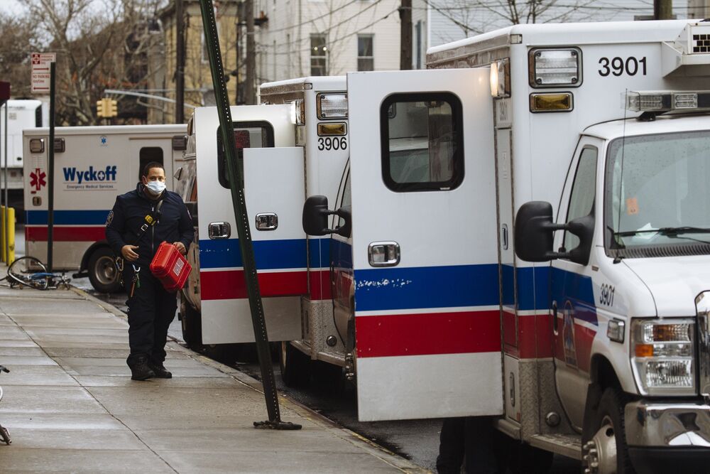 A paramedic wearing a protective mask walks past ambulances in Brooklyn, New York.