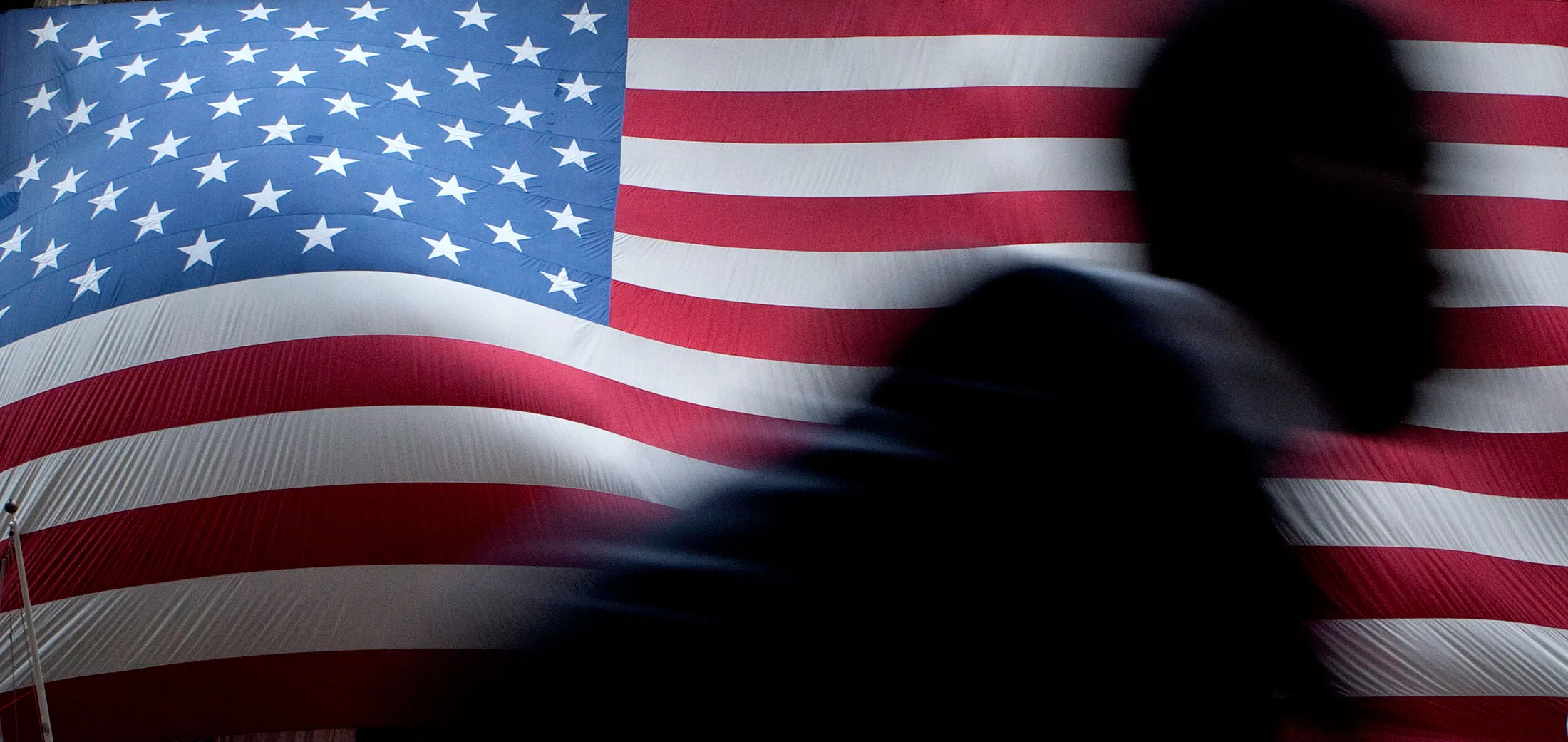 Workers hang a giant American Flag on the exterior of the New York Stock Exchange (NYSE) in New York, U.S., on Friday, May 25, 2012. U.S. stocks rose, giving the Standard &amp; Poor’s 500 Index its first weekly rally since April, as investors were lured by the cheapest valuations since November.
