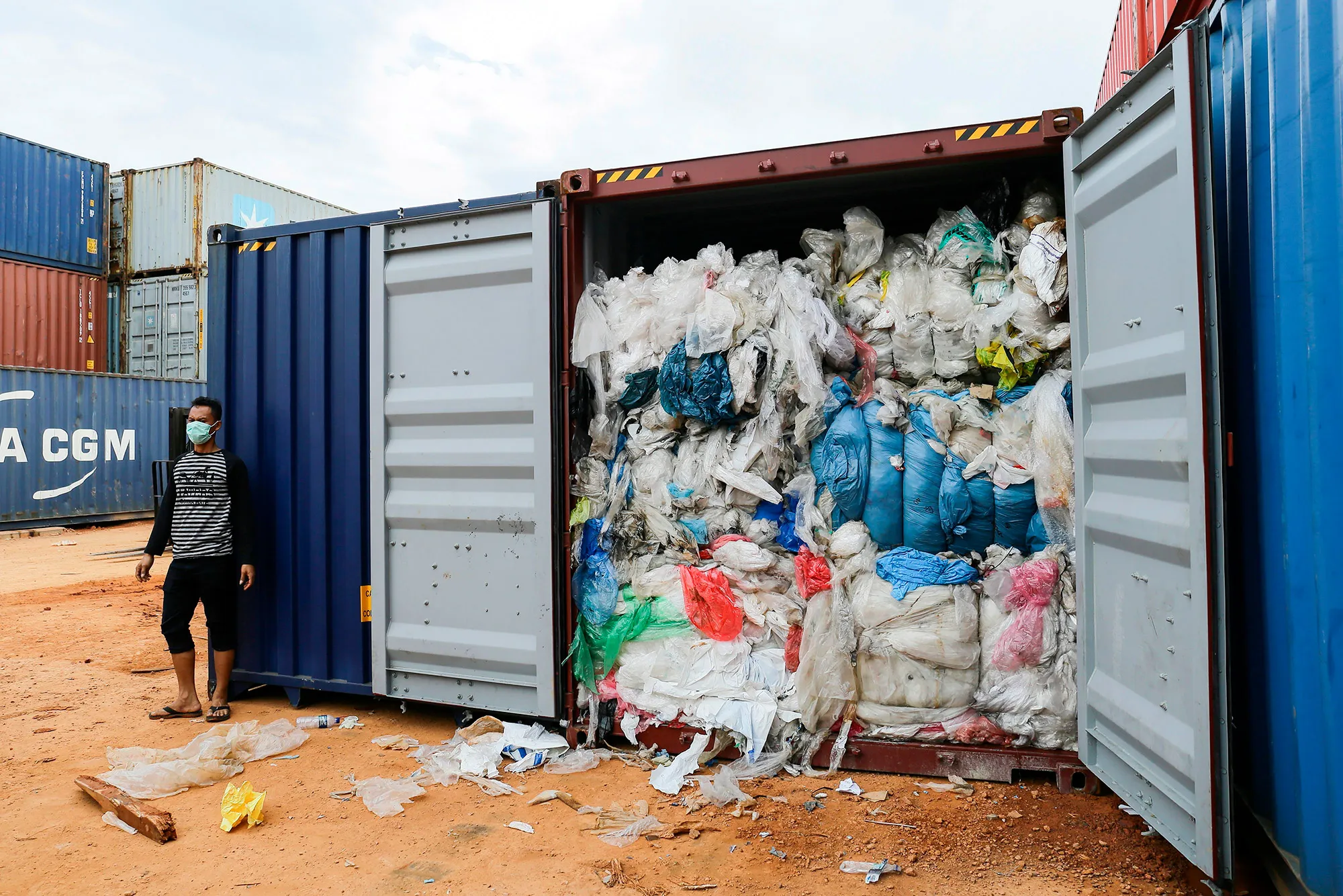 A man stands&nbsp;next to one of 65 containers full of imported plastic rubbish at the Batu Ampar port in Batam.