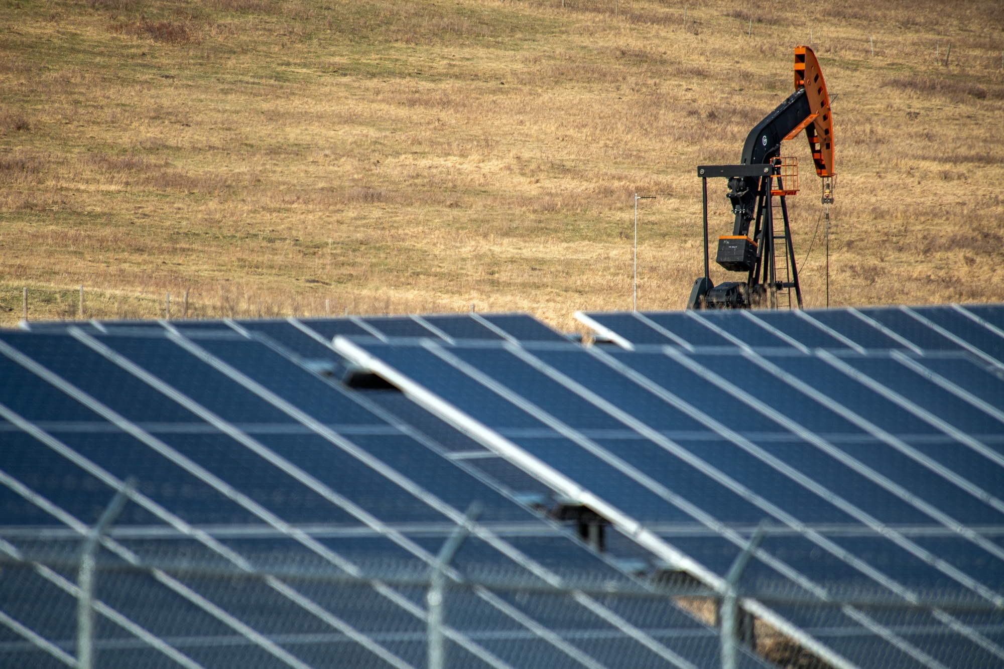 An oil pumpjack behind a bank of solar panels near Longview, Alberta.s plan to meet its 2030 emissions-reduction goal.