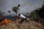 A local resident fights a forest fire with a shovel during a wildfire in Tabara, north-west Spain, July 19, 2022. (Photographer: Bernat Armangue/AP)