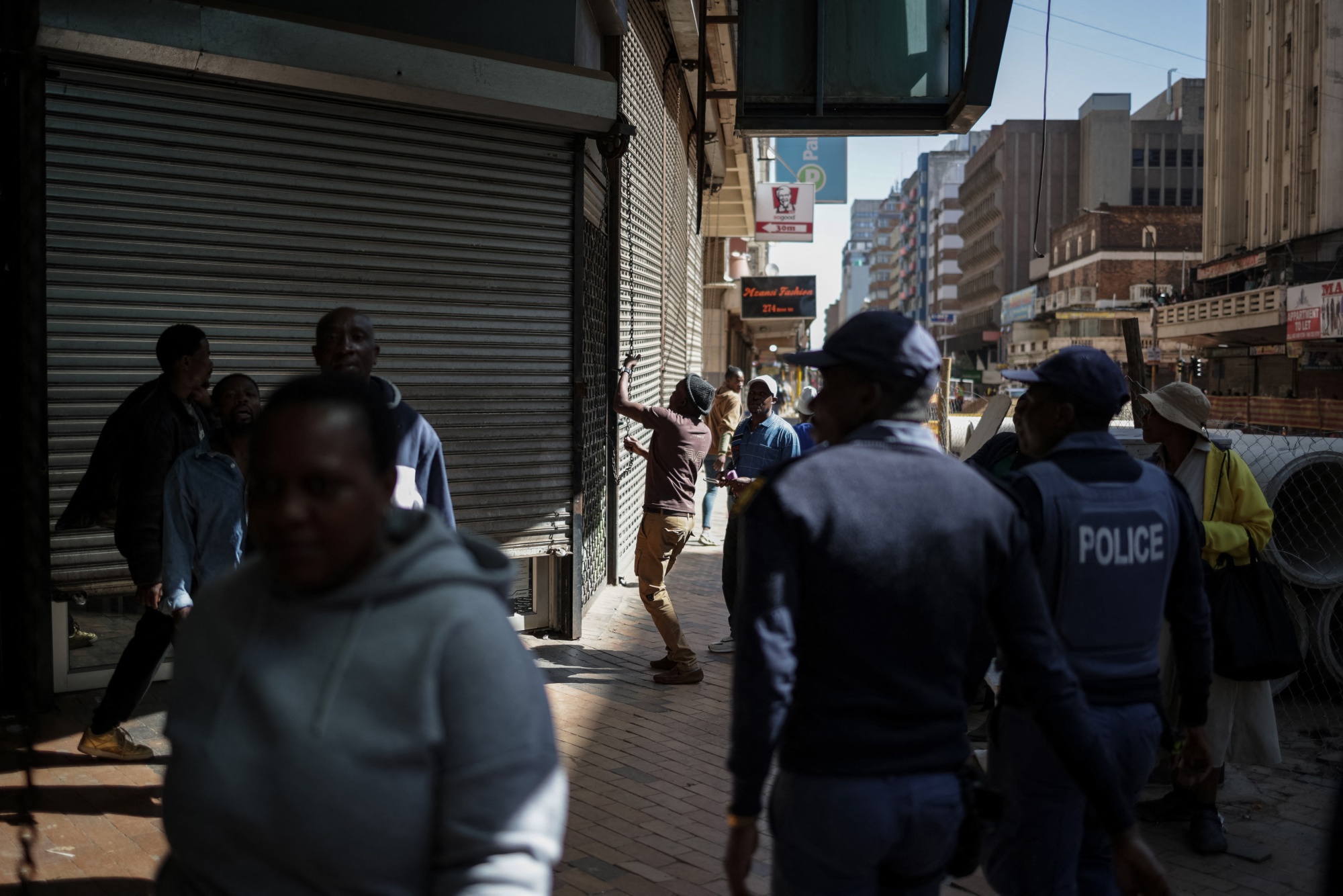 South African police watch a worker shutter a shop during a demonstration against undocumented migrants in Johannesburg on April 29.