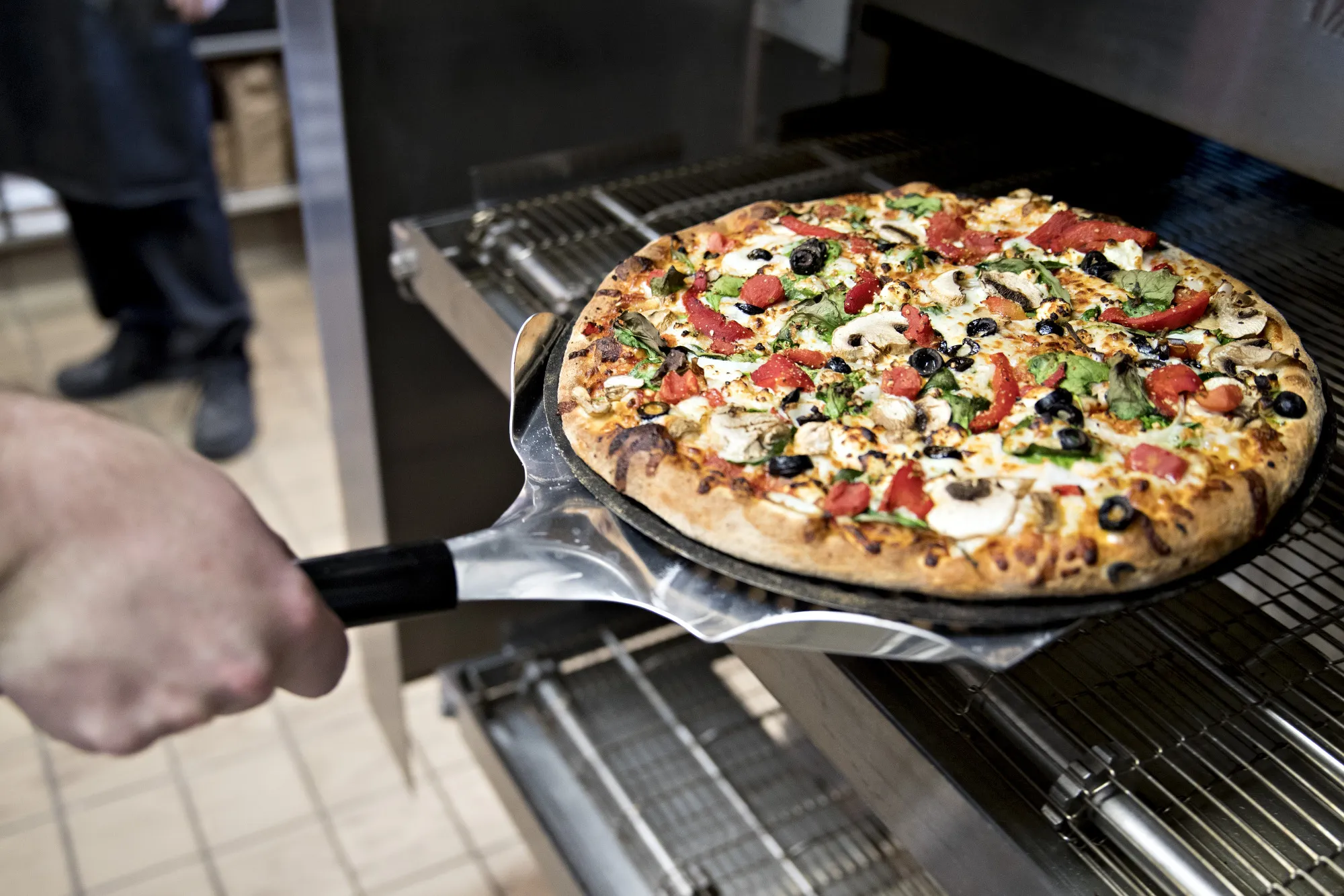 An employee removes a pizza from an oven at a Domino's Pizza Inc. restaurant.