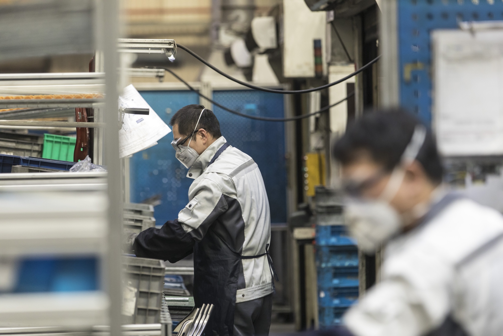 Employees wearing protective face masks work on a production line at a factory in Shanghai.