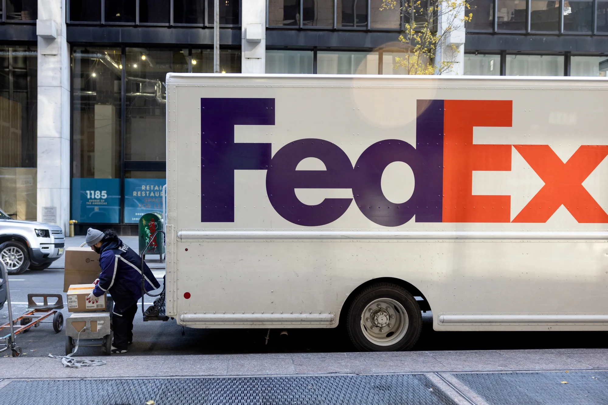 A worker unloads packages from a FedEx truck in New York.