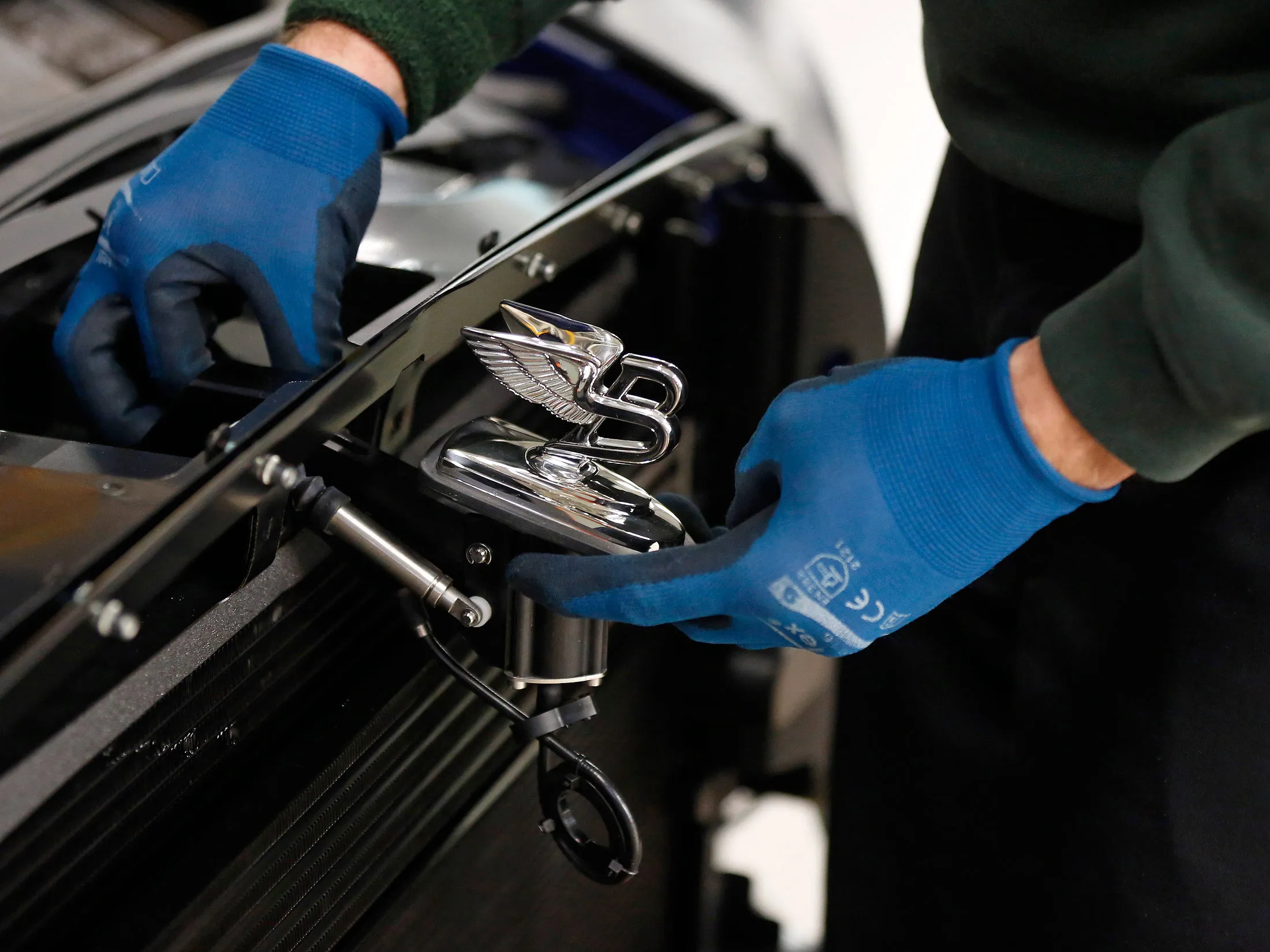 An employee fits a winged 'B' emblem to the hood of a Bentley Mulsanne automobile at the Bentley Motors Ltd. workshop in Crewe, U.K.
