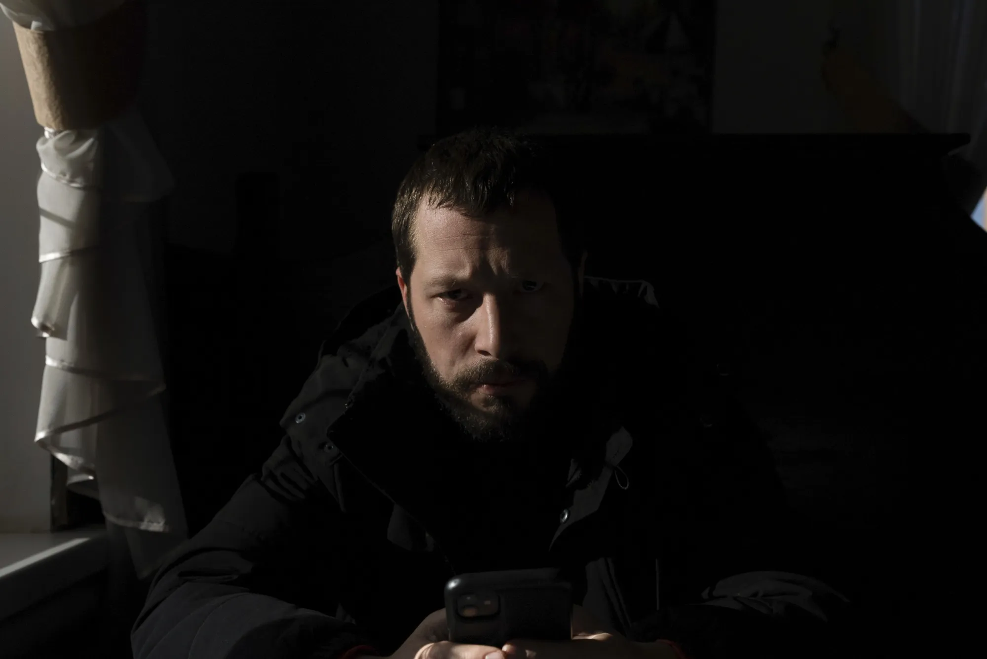 Mstyslav Chernov reads news on his phone three days before the start of Russian invasion in Volnovakha, Ukraine, Feb. 21,&nbsp;