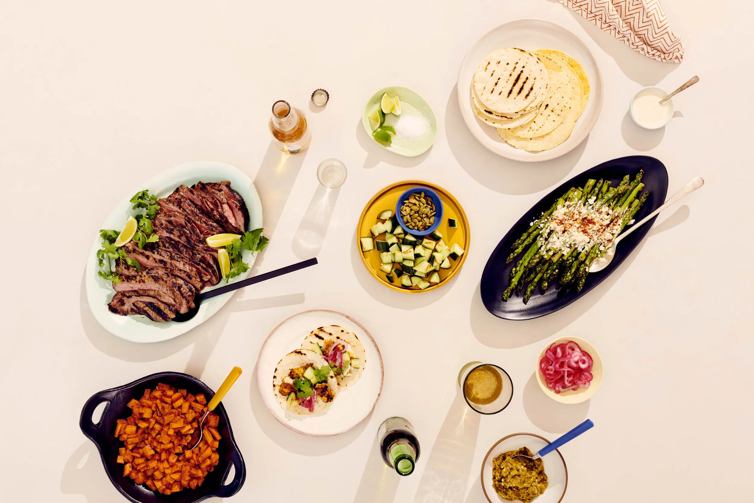 Clockwise from top right: tortillas, lime yogurt, Mexican-style asparagus, pickled onions, salsa verde, achiote grilled fish tacos, mole carrots, carne asada, limes and salt, grillled cucumbers and pepitas.&nbsp;