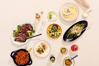 Clockwise from top right: tortillas, lime yogurt, Mexican-style asparagus, pickled onions, salsa verde, achiote grilled fish tacos, mole carrots, carne asada, limes and salt, grillled cucumbers and pepitas.