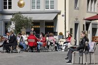 Customers at a cafe outdoor terrace area on a pedestrianized square in Zurich.