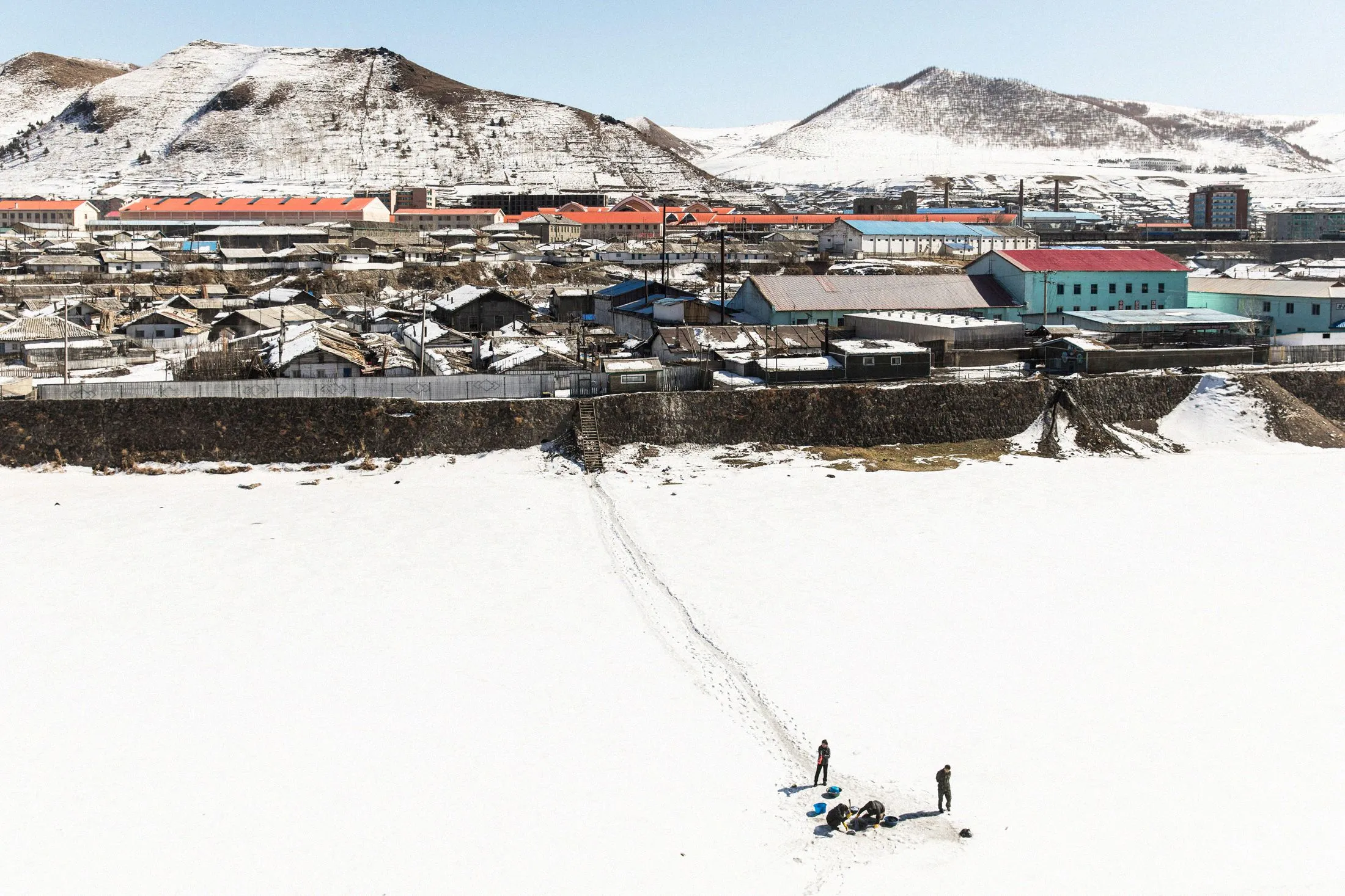 Women wash clothes through a hole in the river ice on the China-North Korea border.