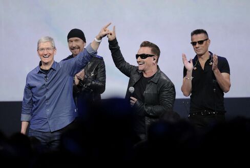 Apple CEO Tim Cook, left, and the band U2 gesture during a product announcement at Flint Center in Cupertino, California, on Sept. 9, 2014.