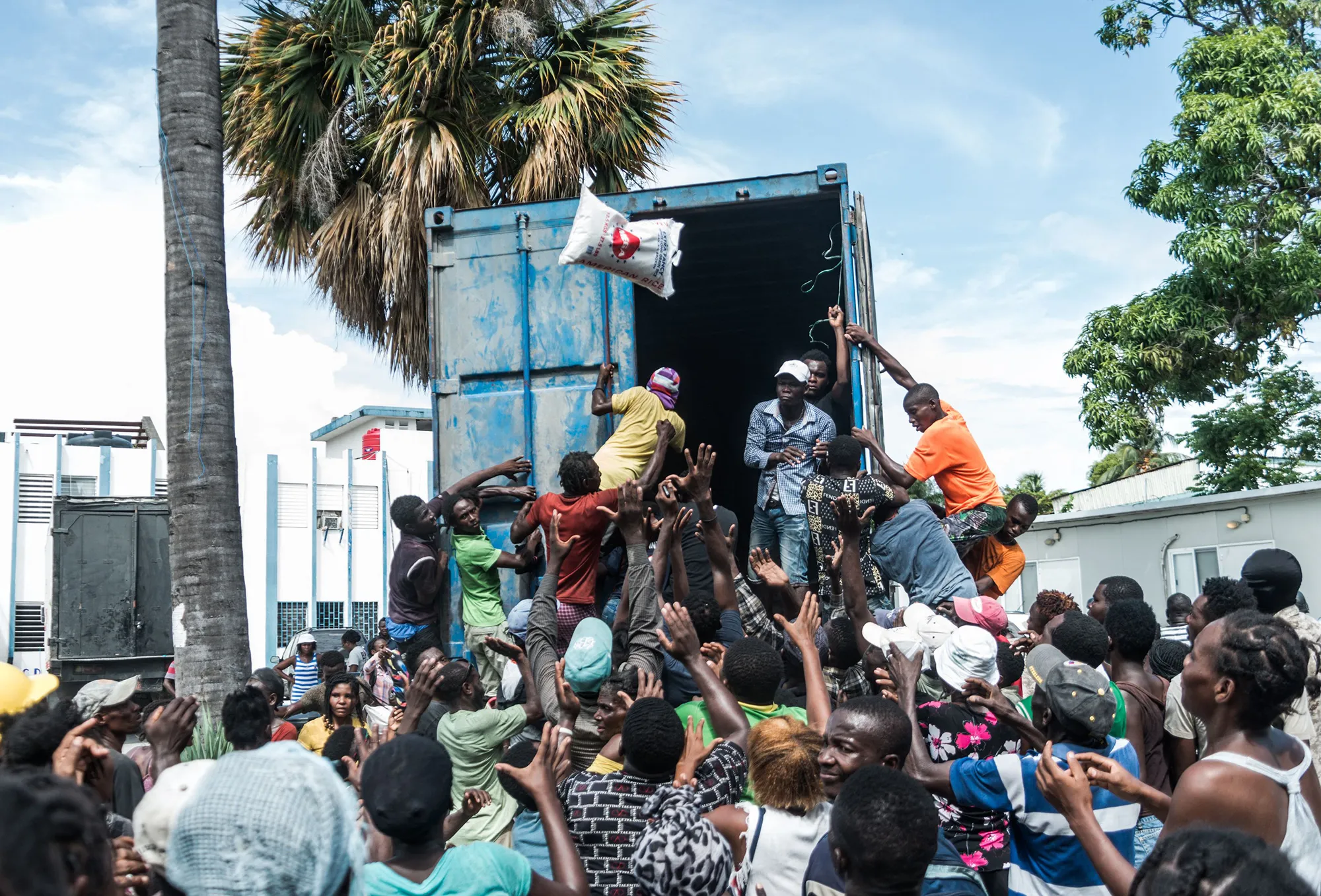 A man throws a bag of rice into a crowd of earthquake victims gathered for the distribution of food and water in Haiti on August 20, 2021.