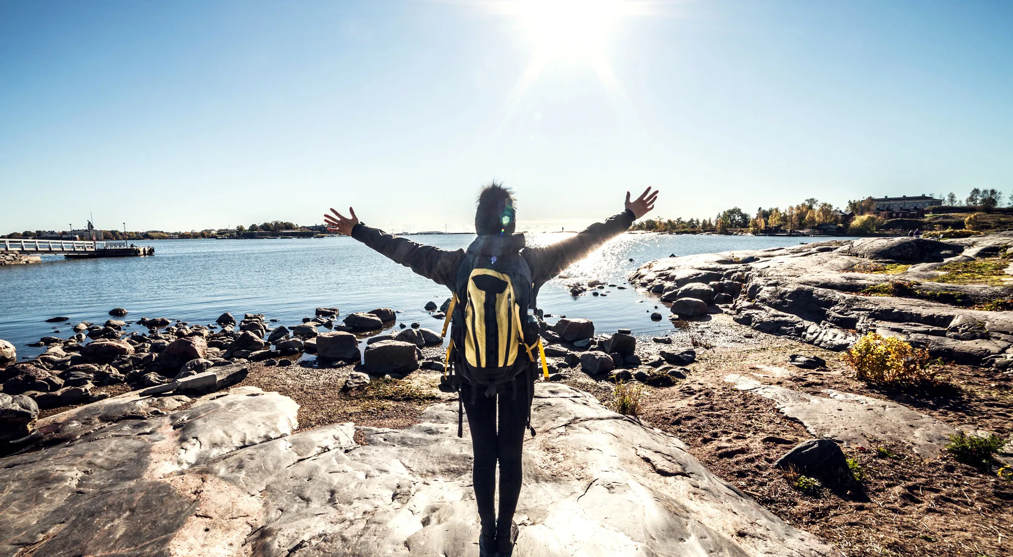 Travel woman arms outstretched by the sea