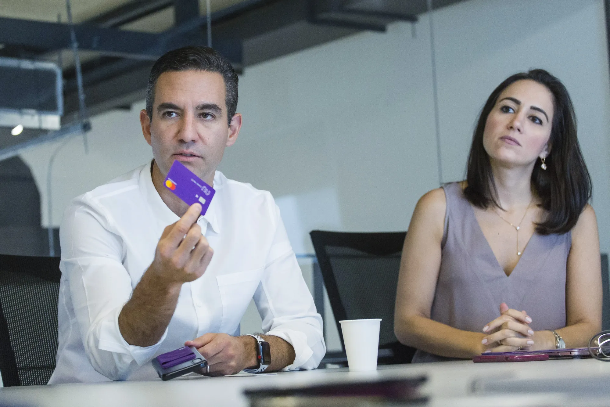 David Velez, founder and chief executive officer of Nubank, left, speaks while holding a credit card as Cristina Junqueira, co-founder and vice president of branding and business development at NuBank, listens during an interview in Sao Paulo, Brazil, on Thursday, Feb. 7, 2019.